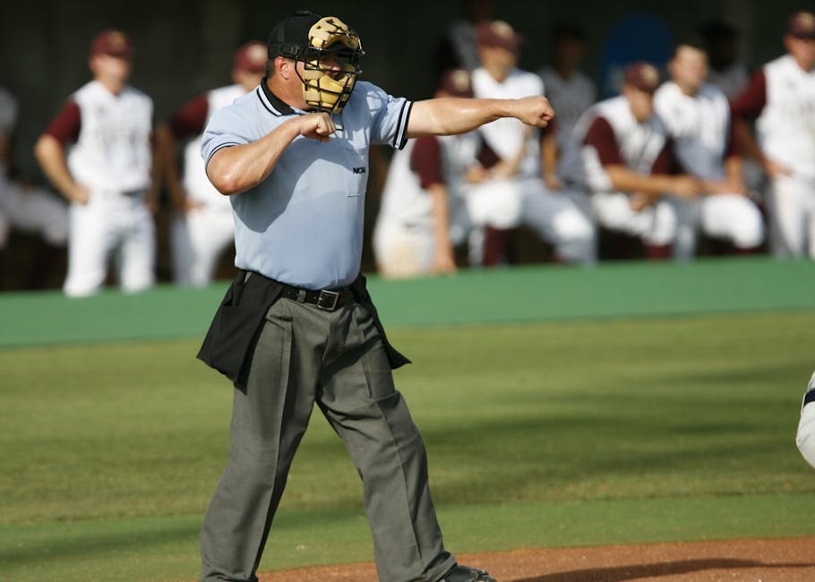 Umpire in action on baseball field with team players in the background.
