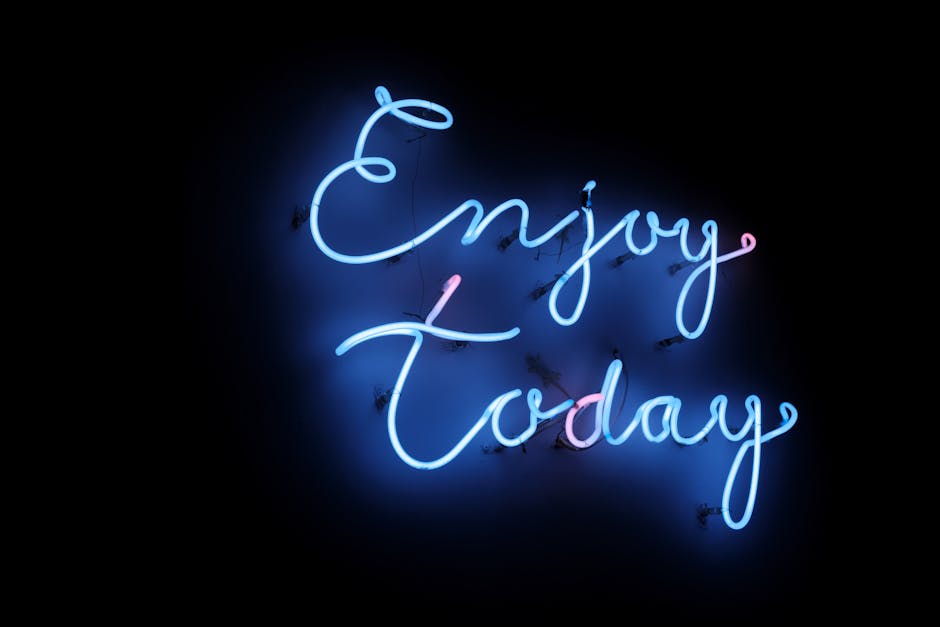 Bright blue neon sign with the phrase ‘Enjoy Today’ on a dark background, creating a vibrant and uplifting atmosphere.
