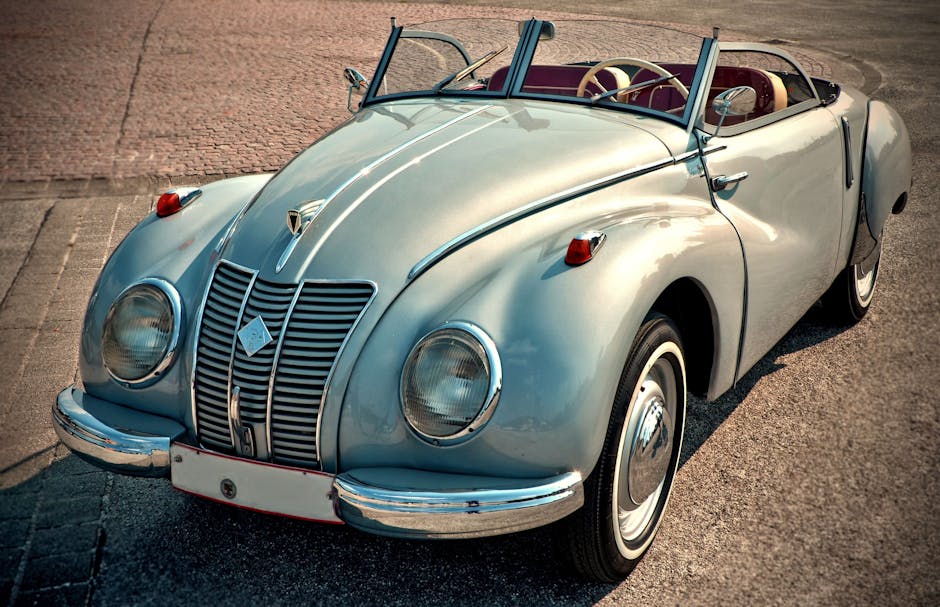 A beautifully restored classic convertible car, featuring chrome details and vintage style, parked on a sunny day.