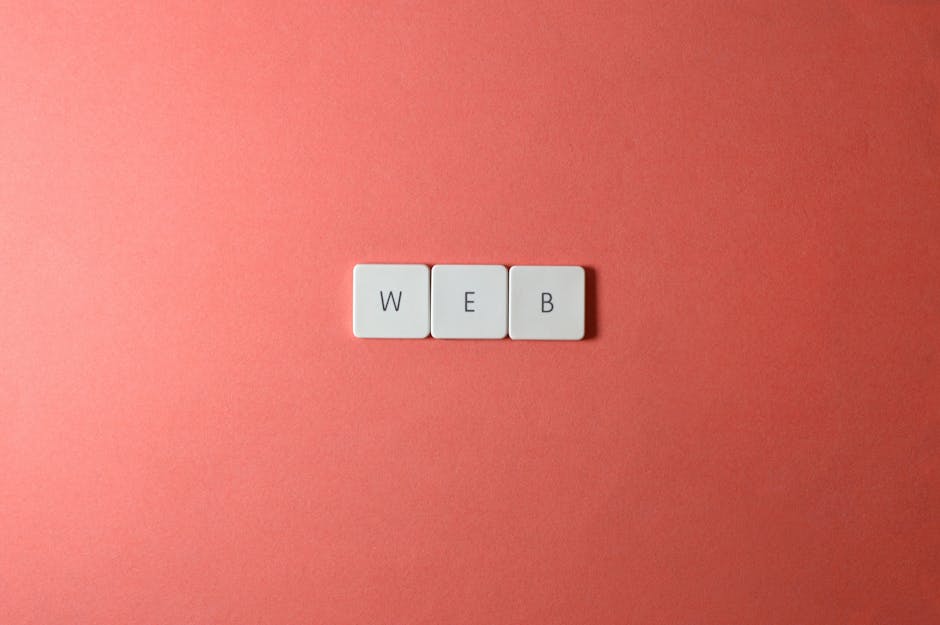 A minimalist photo featuring the word ‘WEB’ spelled with keyboard keys on a red background.