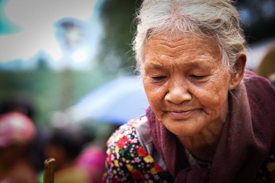 Thoughtful elderly woman in colorful attire outdoors, reflecting on her experiences.