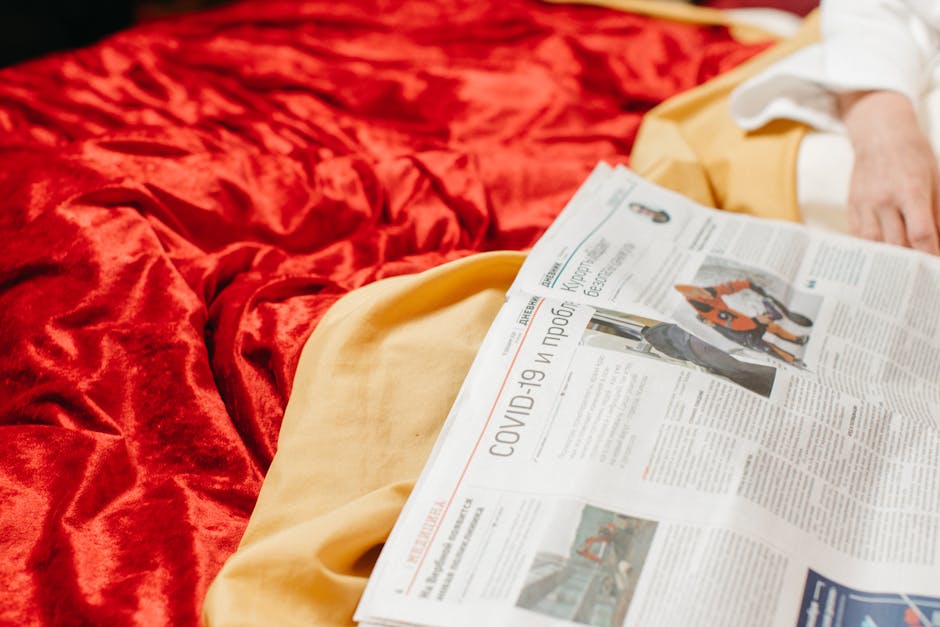 Close-up of a newspaper on a bed with COVID-19 headlines, conveying information and news.