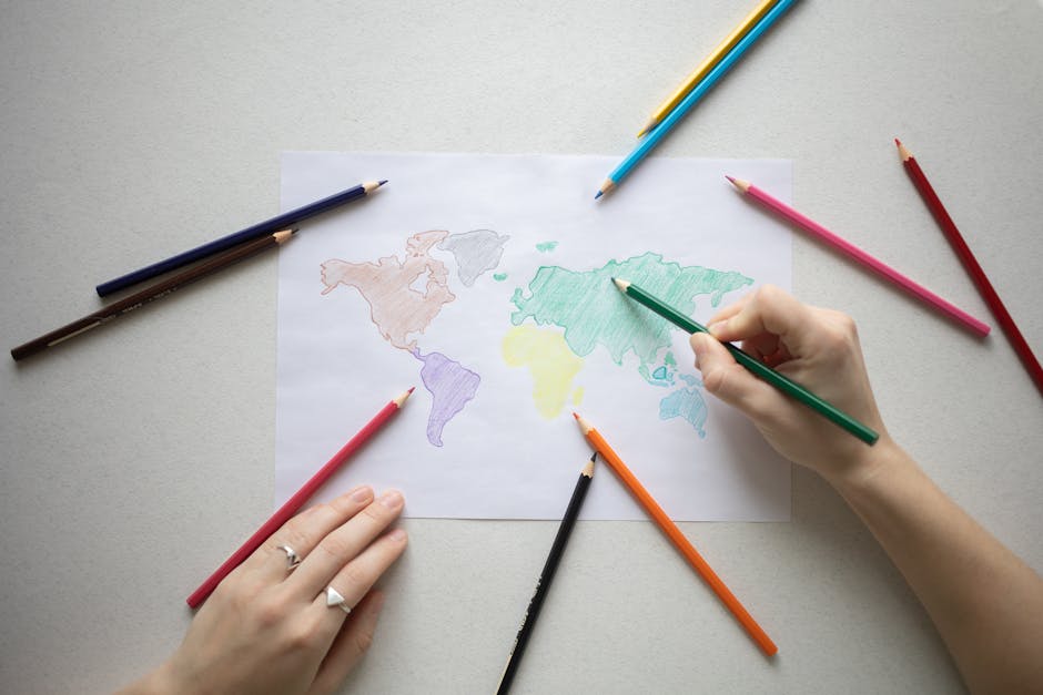 Hands coloring a world map on paper with colorful pencils, creative learning.
