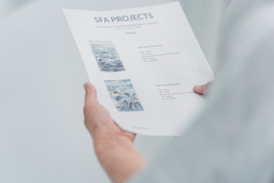 Close-up of hands holding and reading an art project document indoors.