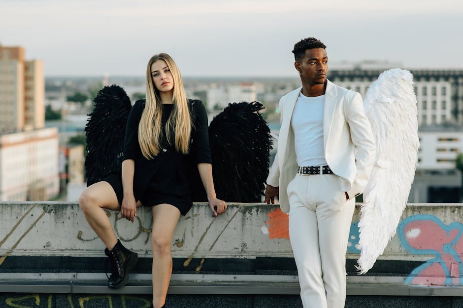 A man and woman dressed as angels on a rooftop, showcasing black and white contrast.