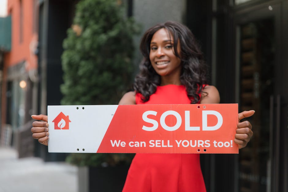 Happy woman in red dress holding a ‘Sold’ sign in an urban setting, promoting real estate sales.