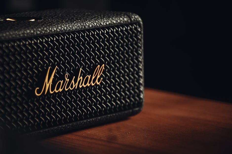 A detailed close-up of a black textured Marshall speaker resting on a wooden surface.