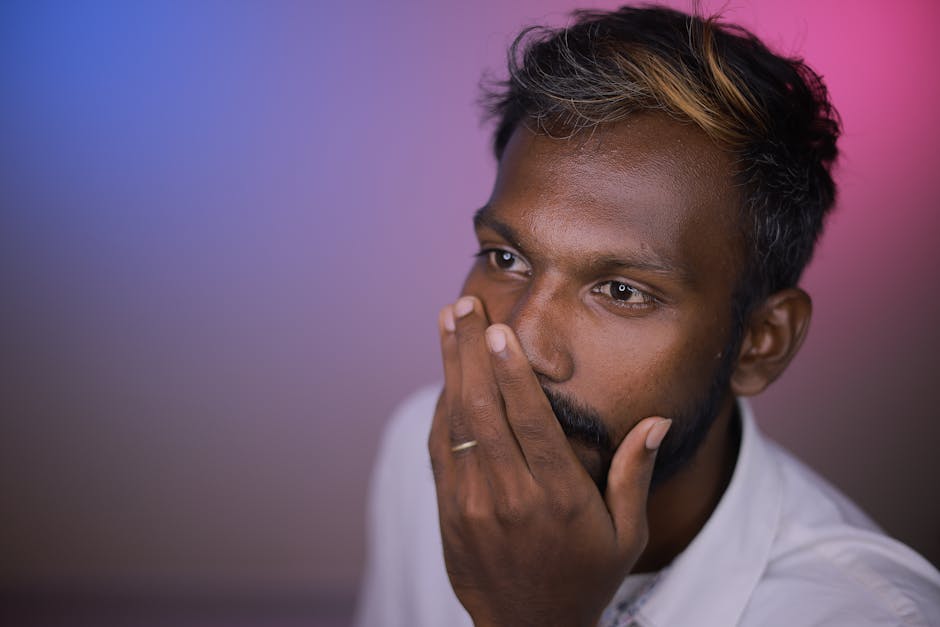 A contemplative man with colored backlighting, expressing pensive emotion