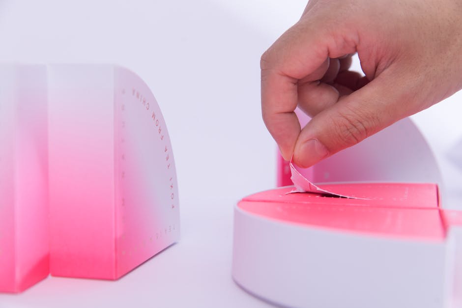 A hand touching a gradient pink and white abstract sculpture in a close-up shot.