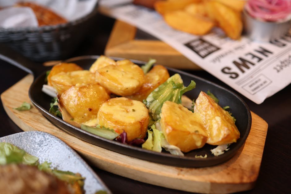 Crispy roasted potatoes on a black skillet, garnished and served with fresh greens.