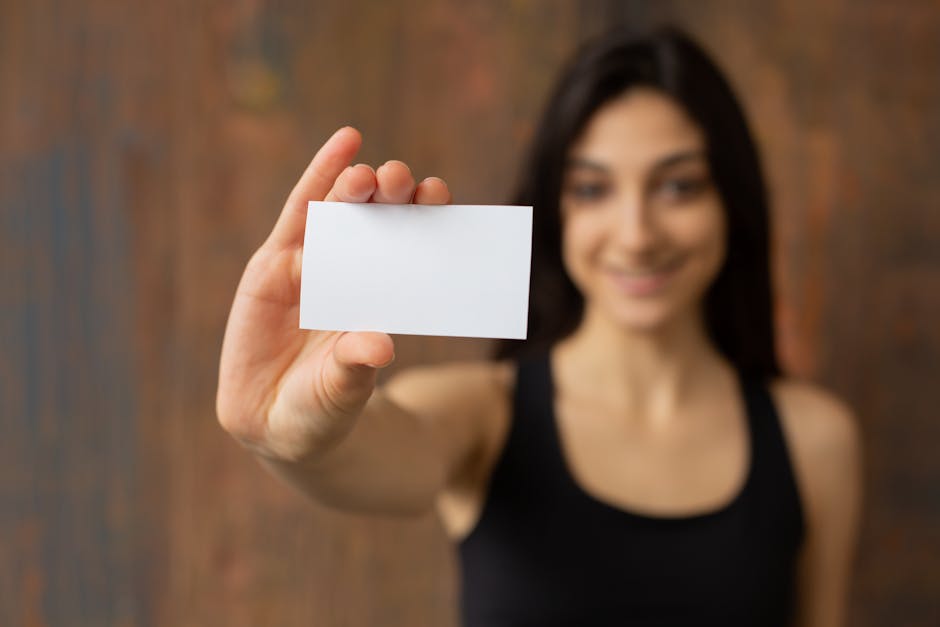 Young woman smiling and showing a blank business card, ideal for design work.