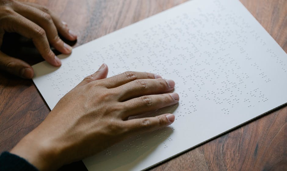 Hands gently read a Braille text sheet providing tactile learning experience.