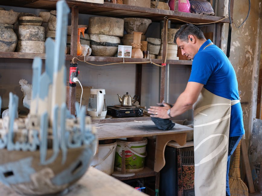 A potter works skillfully with clay in a rustic ceramic studio, surrounded by pottery tools.