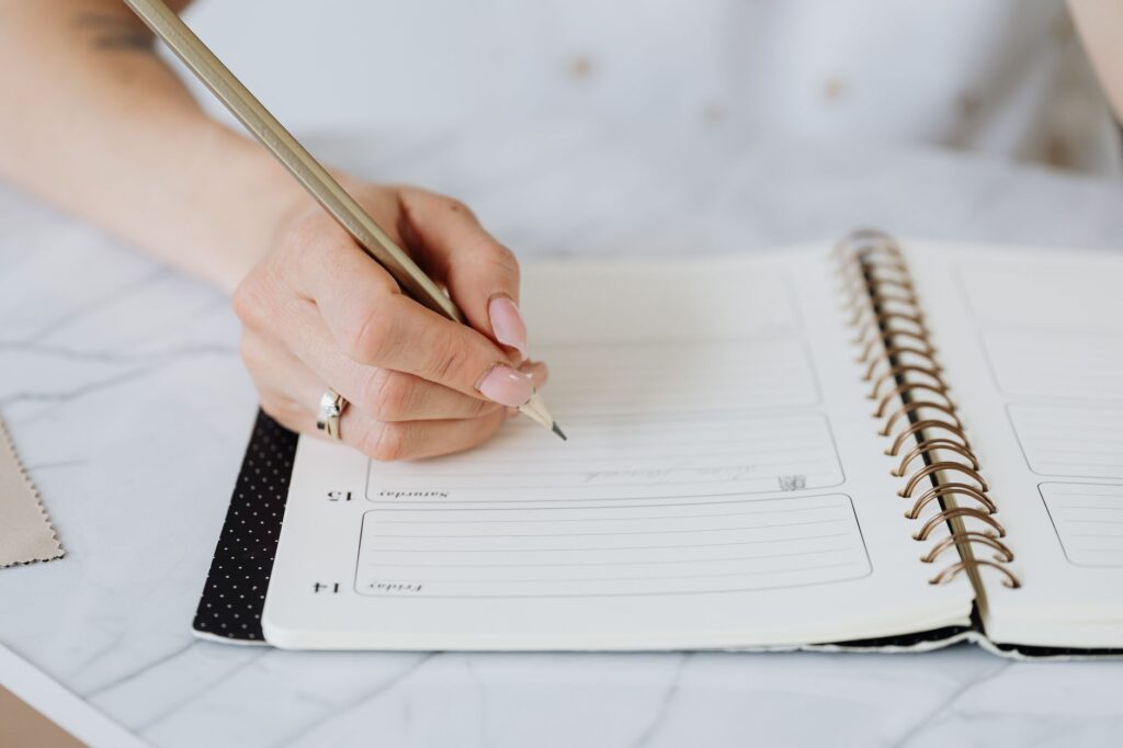 Daily monitoring log on a small notebook with simple bullet entries dated across the week